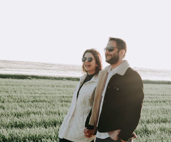 Smiling person stretching outdoors in a green park at sunrise.